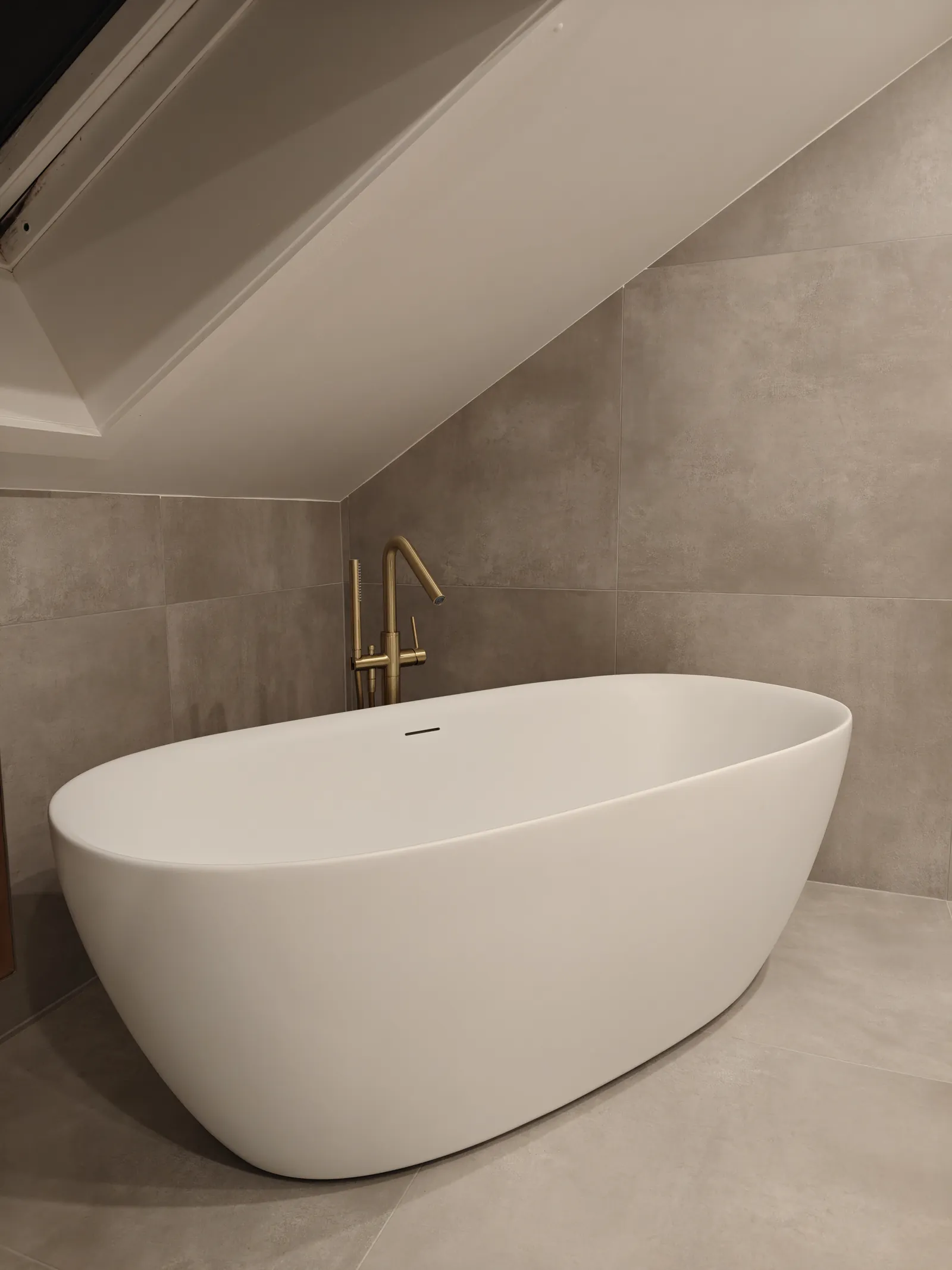Baignoire îlot et robinetterie sur pied dans une salle de bain aux finitions minérales