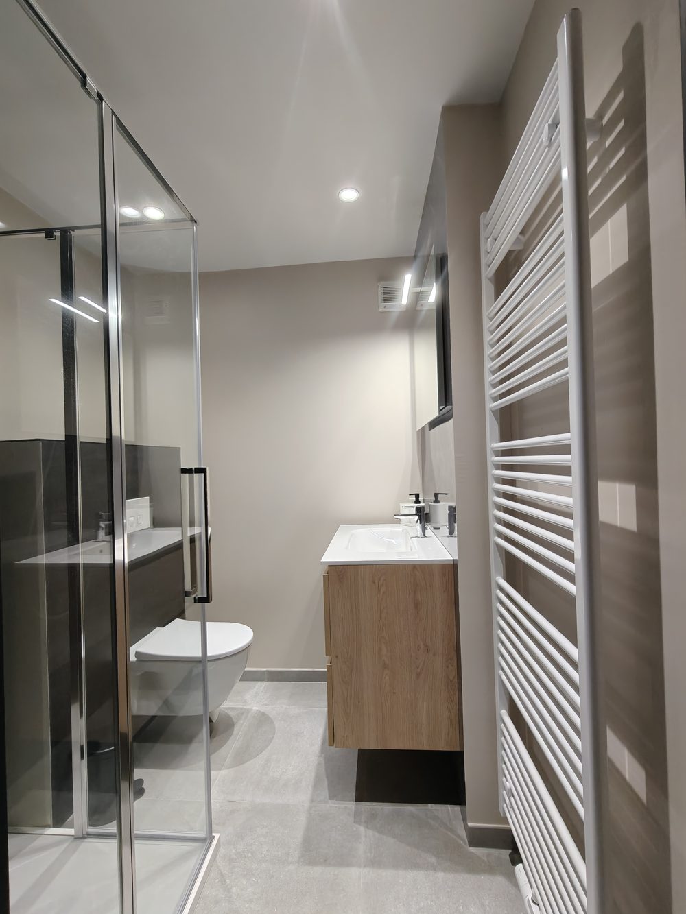 Après travaux : douche vitrée, WC suspendu, meuble vasque en bois et sèche-serviettes